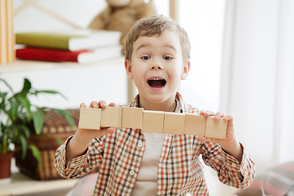 criança a sorrir enquanto está a brincar com blocos de madeira